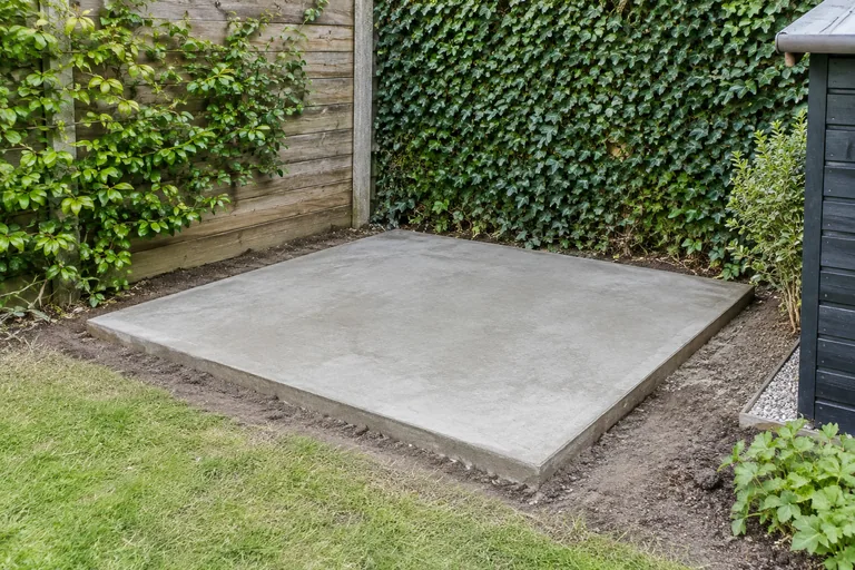 Betonnen plaat op de grond in een achtertuin.