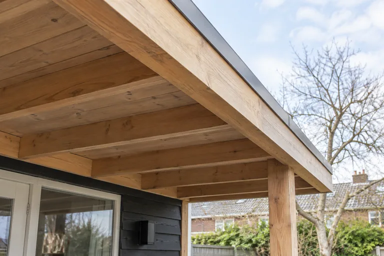 Houten dakoverstek boven een terras aan een woning.