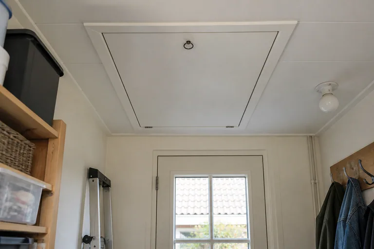 Gesloten wit vlieringluik in het plafond van een bijkeuken.