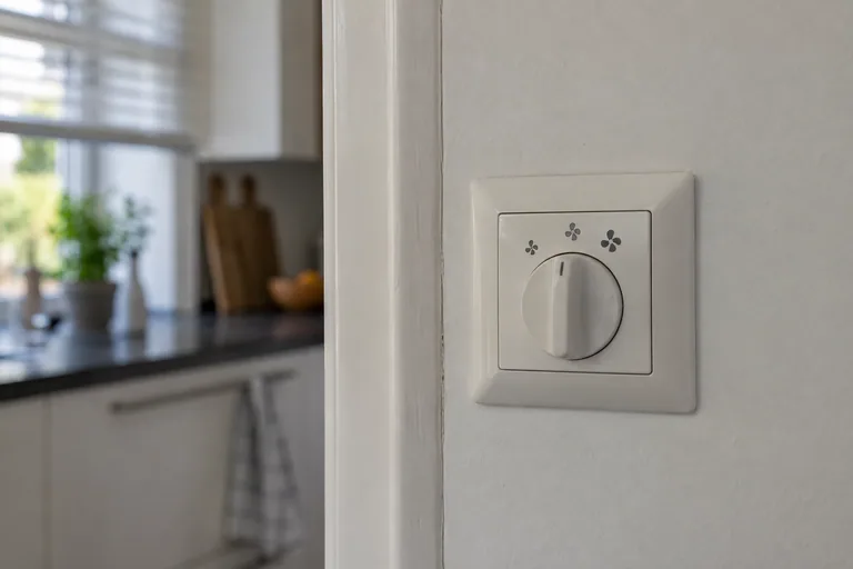 Draaiknop voor ventilatie op een wand bij een keuken.