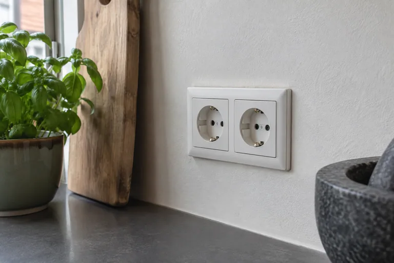 Dubbele witte wandcontactdoos in een keukenwand.