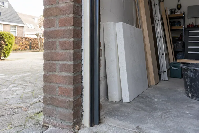 Zichtbare gemetselde dagkant bij een garageopening met losse isolatieplaten.