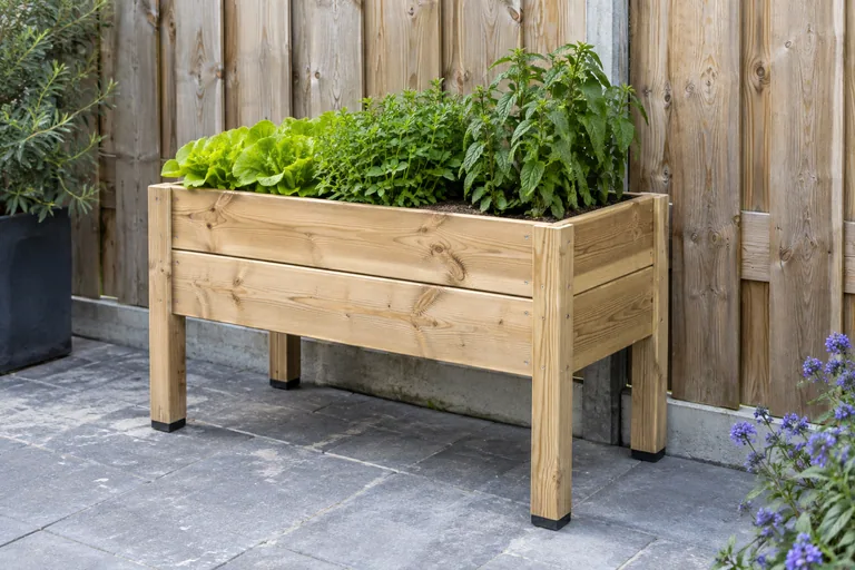 Vrijstaande houten plantenbak op poten voor een schutting.