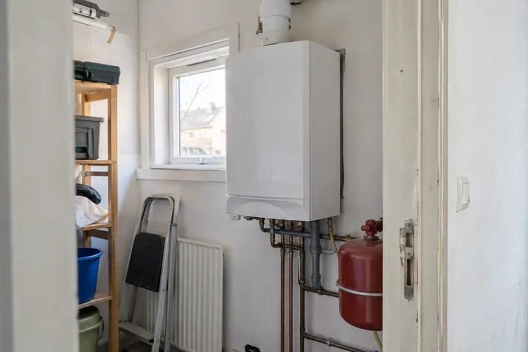 Gesloten witte cv-ketel in een kleine bijkeuken.
