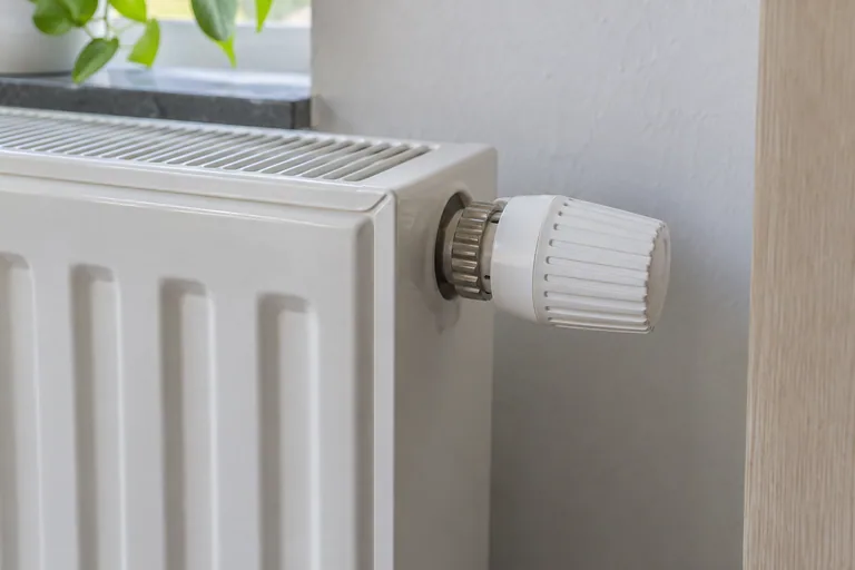 Witte radiatorknop aan de zijkant van een paneelradiator.