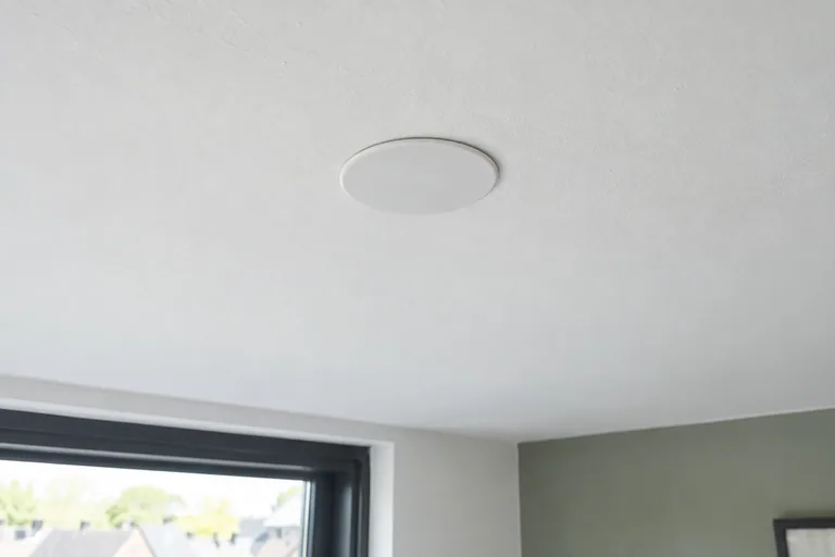 Ronde witte afdekplaat op een wit plafond.