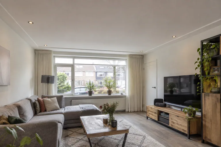 Afgewerkt wit plafond met inbouwspots in een woonkamer.