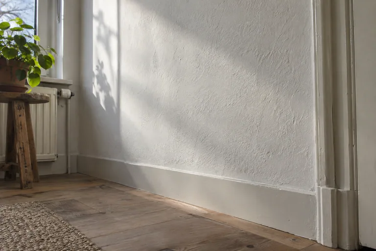 Zijlicht langs een witte wand maakt oneffenheden zichtbaar.