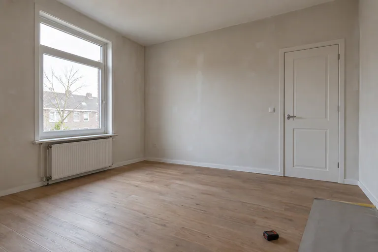 Lege kamer met raam, deur, vloer en een meetapparaat.